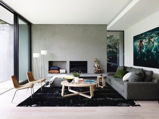 Cozy-living-room-design-with-painting-on-white-walls-equipped-black-fireplace-sofa-cushion-circle-wood-tables-carpets-standing-lamps-lacquered-floor