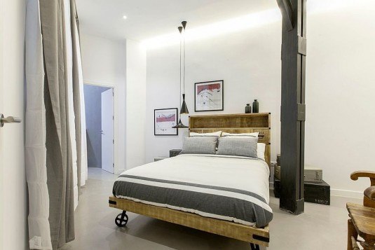 Industrial-bedroom-with-Tom-Dixon-pendant-lighting-and-a-bed-on-wheels